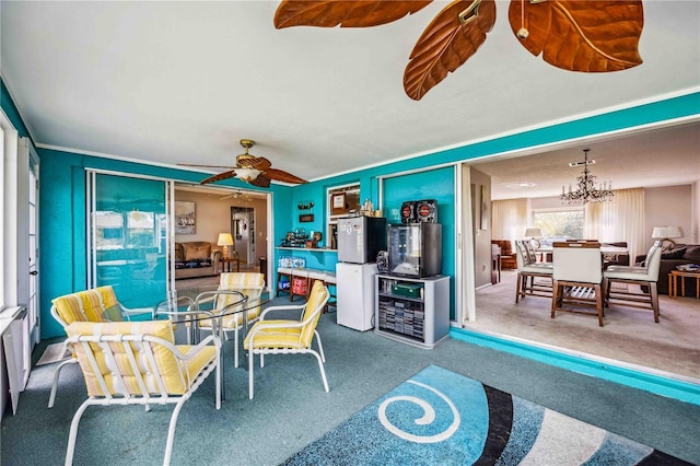 interior space featuring carpet floors and ceiling fan with notable chandelier