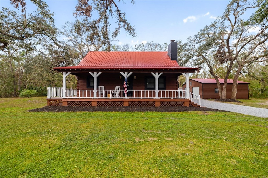 farmhouse inspired home featuring a porch, a garage, an outdoor structure, and a front yard