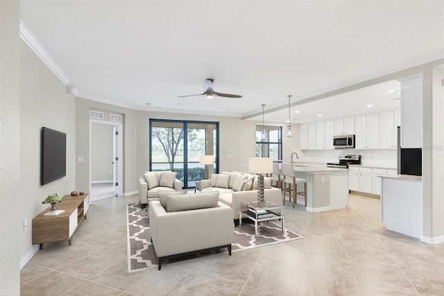 tiled living room featuring sink, crown molding, and ceiling fan