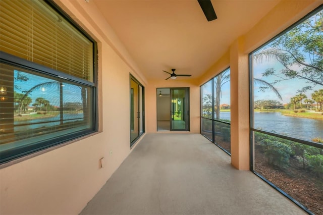 unfurnished sunroom featuring a water view and ceiling fan