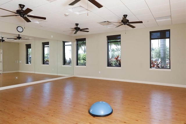 exercise area with a paneled ceiling and light hardwood / wood-style floors