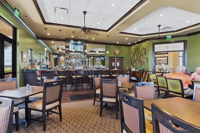 dining room with a tray ceiling, ornamental molding, and indoor bar