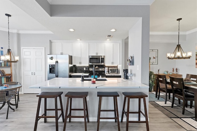 kitchen with white cabinetry, stainless steel appliances, and ornamental molding