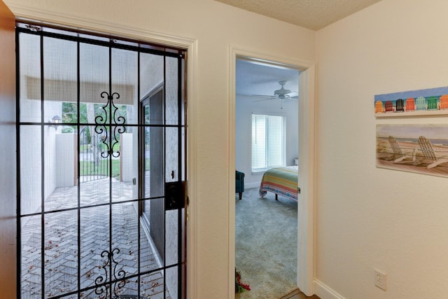 entryway featuring carpet flooring, ceiling fan, and a textured ceiling