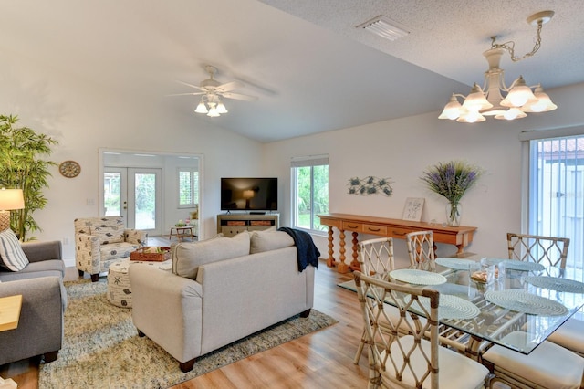 living room featuring vaulted ceiling, light hardwood / wood-style flooring, a textured ceiling, and ceiling fan with notable chandelier