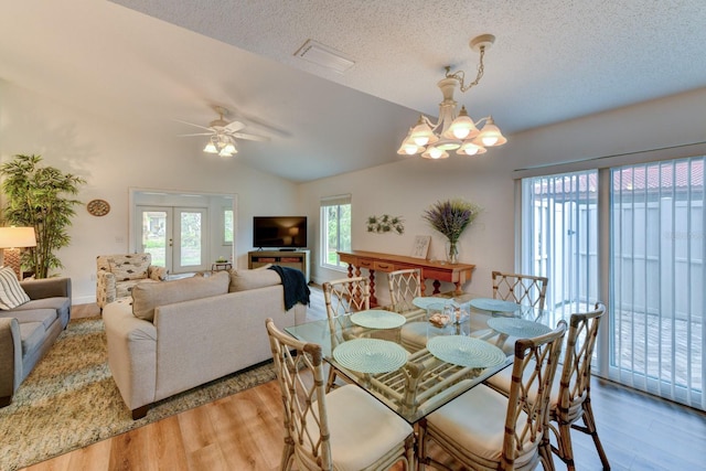 dining area featuring ceiling fan with notable chandelier, a healthy amount of sunlight, a textured ceiling, and vaulted ceiling