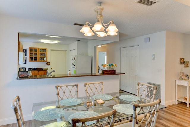 dining room featuring a chandelier, a textured ceiling, light wood-type flooring, and sink