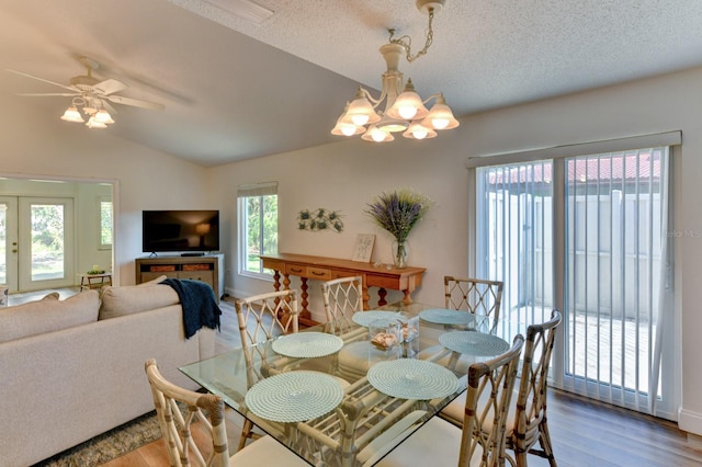 dining space with vaulted ceiling, a wealth of natural light, a textured ceiling, and ceiling fan with notable chandelier