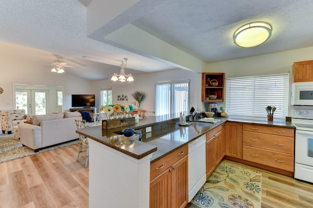 kitchen featuring light hardwood / wood-style floors, white appliances, kitchen peninsula, and sink