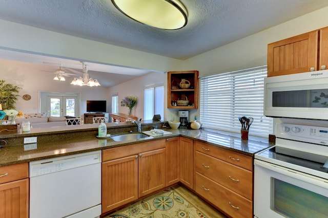 kitchen with white appliances, french doors, sink, dark stone countertops, and a textured ceiling