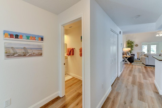 hall with light hardwood / wood-style flooring and a textured ceiling