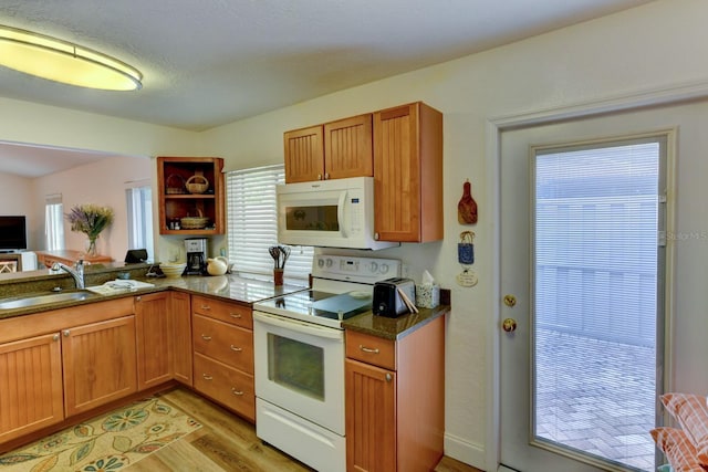 kitchen featuring dark stone countertops, sink, white appliances, and light hardwood / wood-style flooring