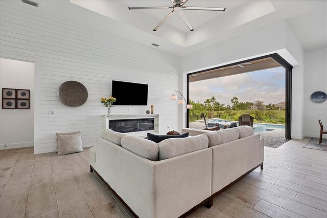 living room featuring a tray ceiling, light hardwood / wood-style flooring, and ceiling fan