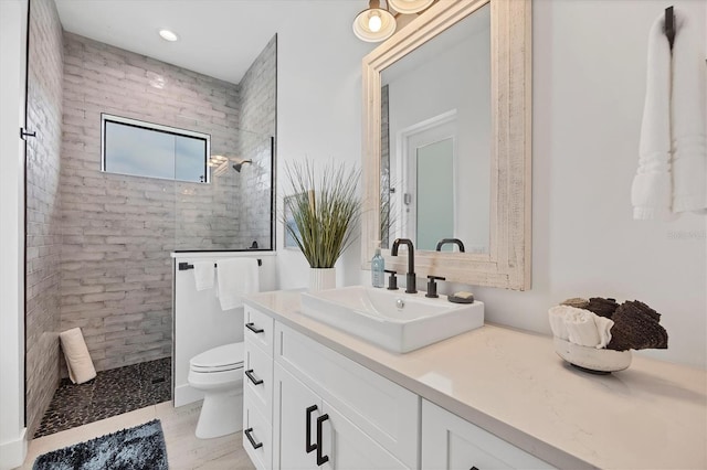 bathroom featuring tiled shower, vanity, and toilet