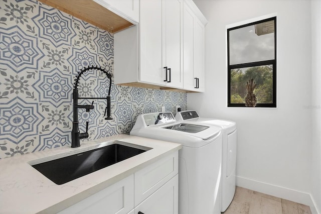 washroom featuring light hardwood / wood-style floors, washer and clothes dryer, cabinets, and sink