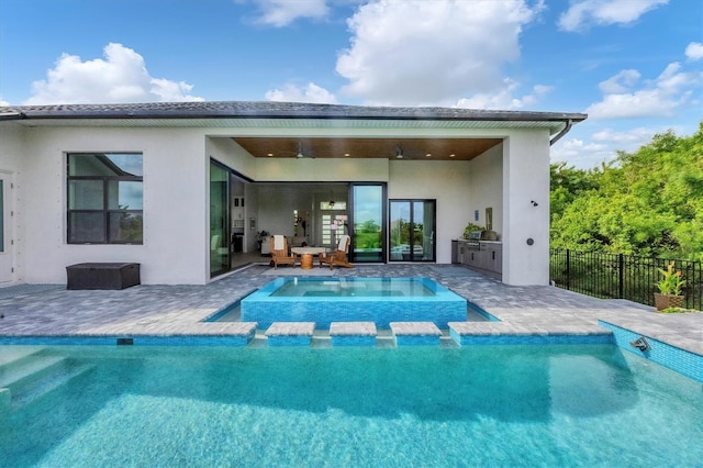 rear view of house featuring an outdoor kitchen, a fenced in pool, and a patio area