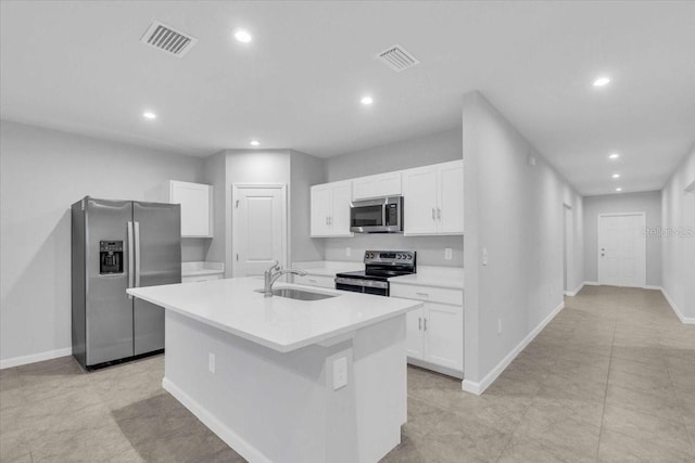 kitchen featuring light tile patterned floors, a center island with sink, stainless steel appliances, white cabinets, and sink