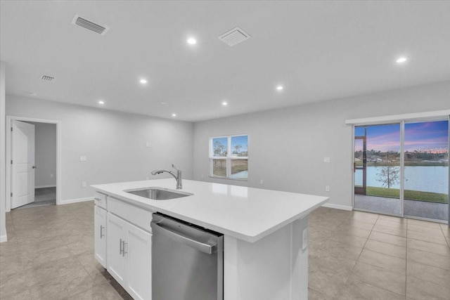 kitchen featuring a kitchen island with sink, light tile patterned flooring, dishwasher, white cabinets, and sink