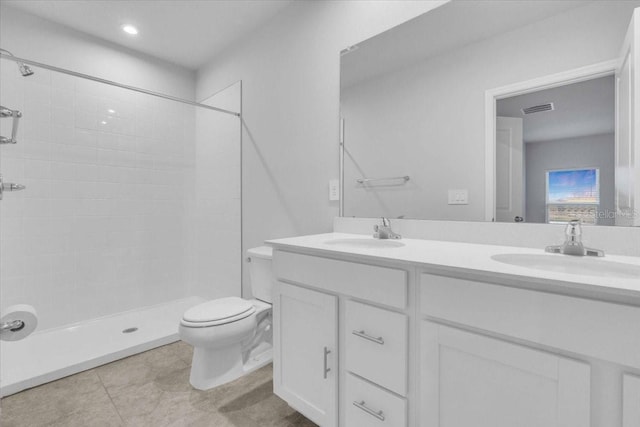 bathroom featuring toilet, vanity, and a tile shower