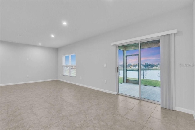 empty room featuring light tile patterned floors and a water view