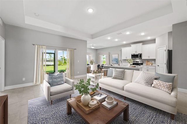 living room with a tray ceiling and sink