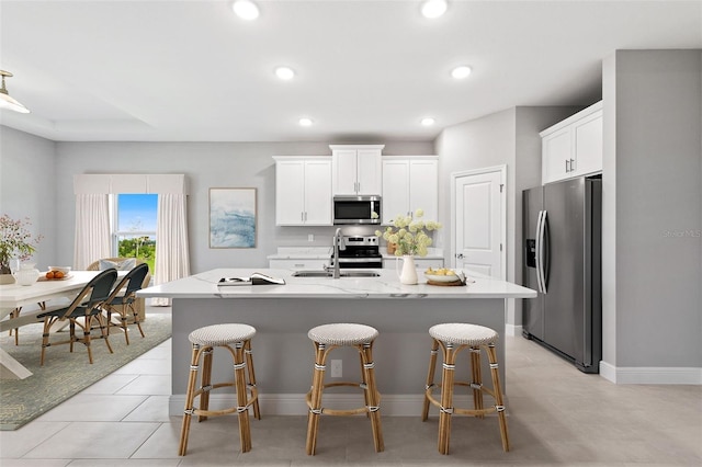 kitchen featuring a center island with sink, white cabinets, and stainless steel appliances