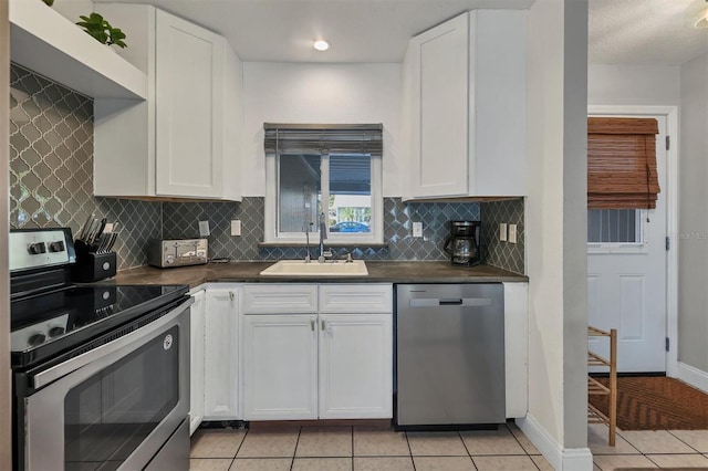 kitchen with decorative backsplash, stainless steel appliances, sink, white cabinets, and light tile patterned flooring