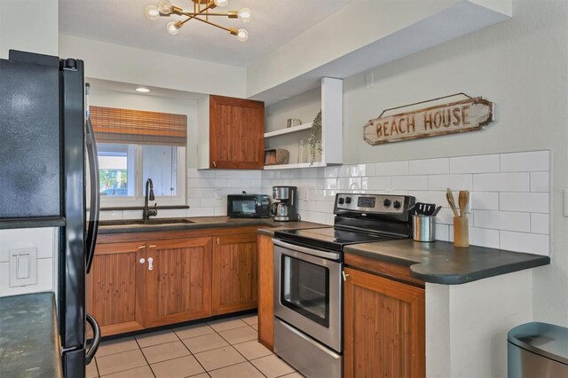 kitchen featuring an inviting chandelier, black appliances, sink, decorative backsplash, and light tile patterned floors