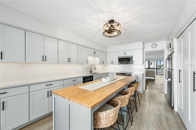 kitchen with a breakfast bar, backsplash, sink, a kitchen island, and stainless steel appliances