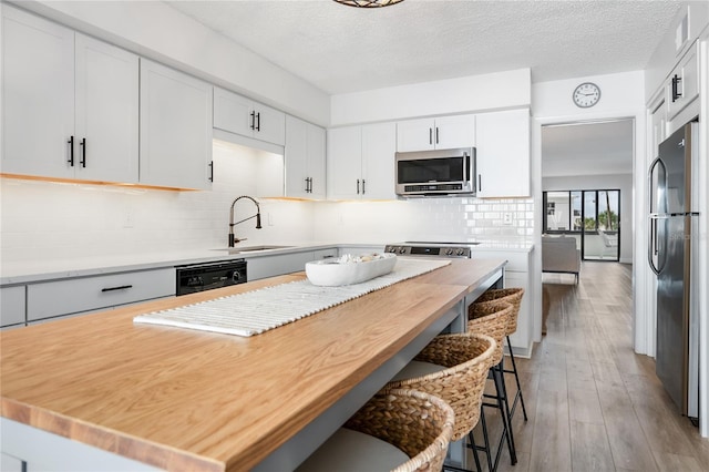 kitchen featuring white cabinets, sink, a kitchen bar, and stainless steel appliances