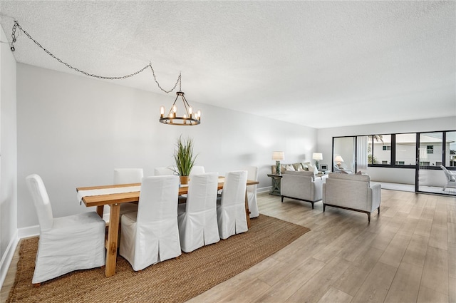 dining room with a textured ceiling, light hardwood / wood-style flooring, and a notable chandelier