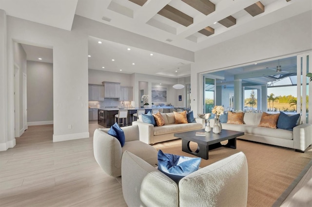 living room featuring ceiling fan, beamed ceiling, and a high ceiling