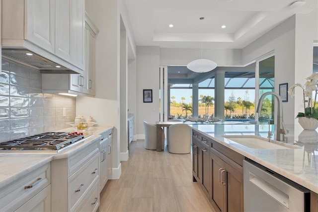 kitchen featuring light stone countertops, sink, stainless steel appliances, a raised ceiling, and white cabinets