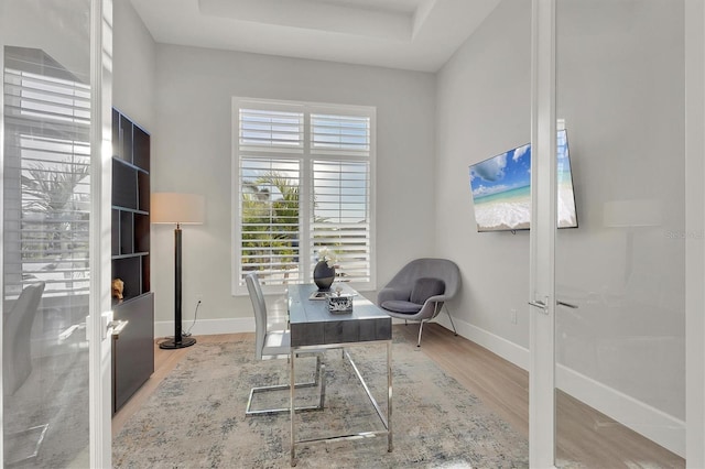 office area featuring hardwood / wood-style floors, a raised ceiling, and french doors