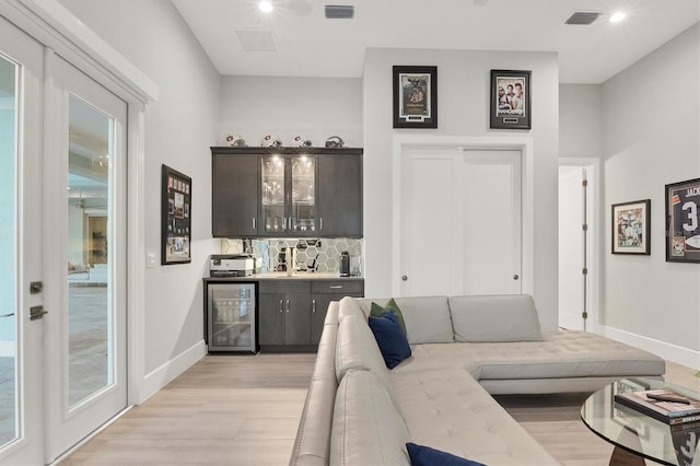 living room featuring light hardwood / wood-style floors, wine cooler, and bar area