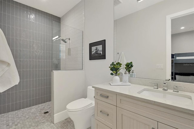 bathroom featuring tile patterned floors, vanity, toilet, and tiled shower