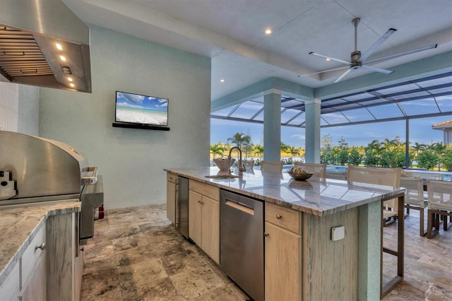 kitchen featuring stainless steel dishwasher, a healthy amount of sunlight, sink, light brown cabinets, and an island with sink