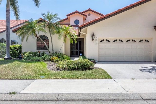 mediterranean / spanish home featuring a front lawn and a garage