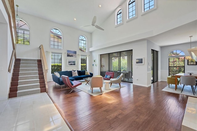 living room with ceiling fan, plenty of natural light, a towering ceiling, and light hardwood / wood-style floors