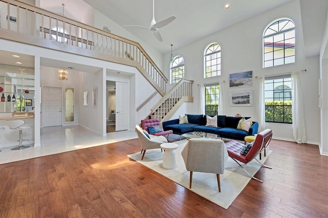 living room featuring a towering ceiling, hardwood / wood-style flooring, and ceiling fan