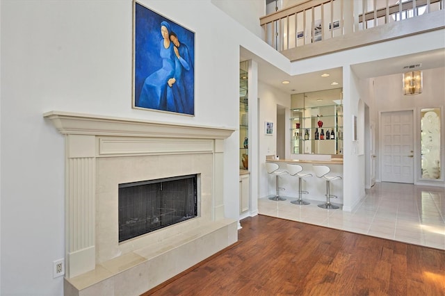 unfurnished living room with hardwood / wood-style floors, a premium fireplace, and a towering ceiling