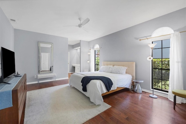 bedroom featuring multiple windows, ceiling fan, hardwood / wood-style floors, and ensuite bath