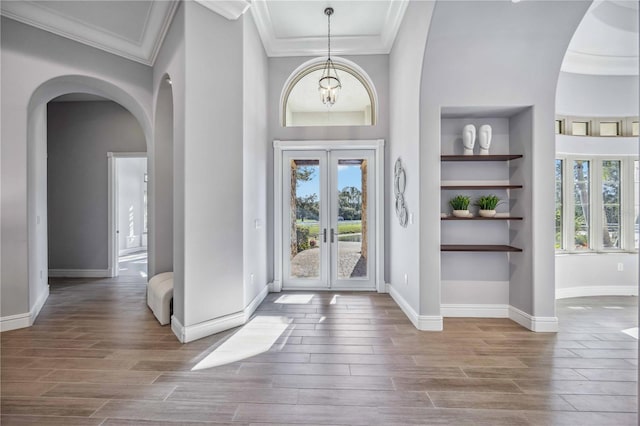 entryway with ornamental molding, a wealth of natural light, and french doors