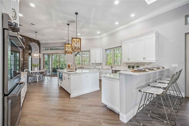 kitchen featuring a center island, sink, decorative light fixtures, a breakfast bar, and white cabinets