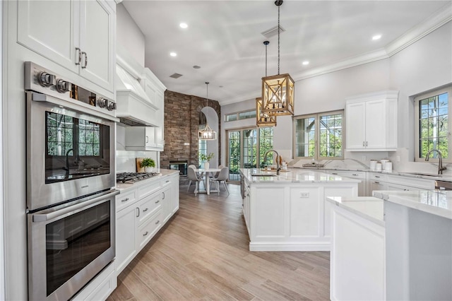 kitchen with pendant lighting, sink, white cabinetry, and a kitchen island with sink