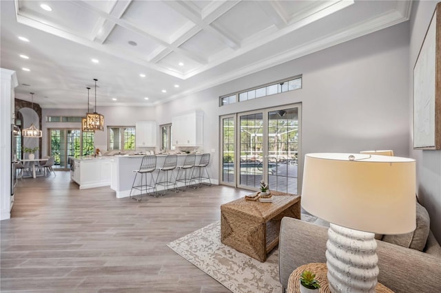 living room with beamed ceiling, light hardwood / wood-style flooring, a healthy amount of sunlight, and coffered ceiling