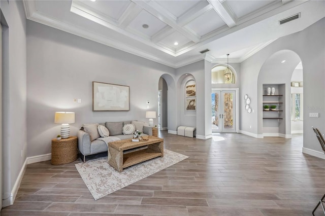 living room with hardwood / wood-style floors, coffered ceiling, crown molding, built in shelves, and beam ceiling