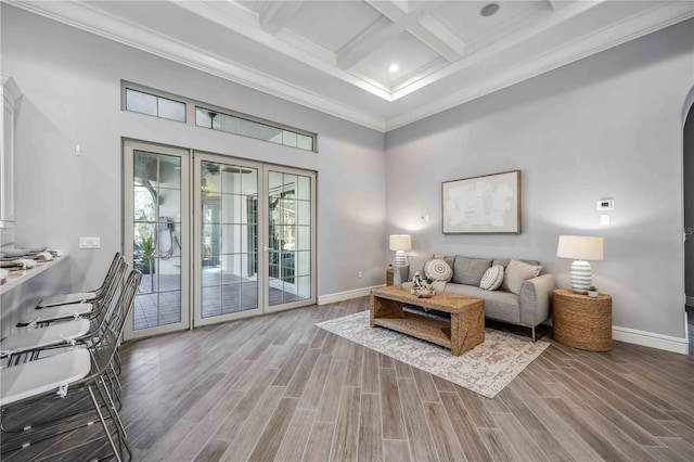 living room with a towering ceiling, coffered ceiling, crown molding, hardwood / wood-style flooring, and beamed ceiling