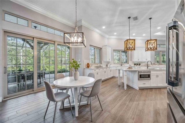 dining area with light wood-type flooring, plenty of natural light, and ornamental molding