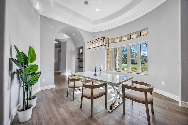 dining area with hardwood / wood-style floors, built in shelves, crown molding, and a tray ceiling